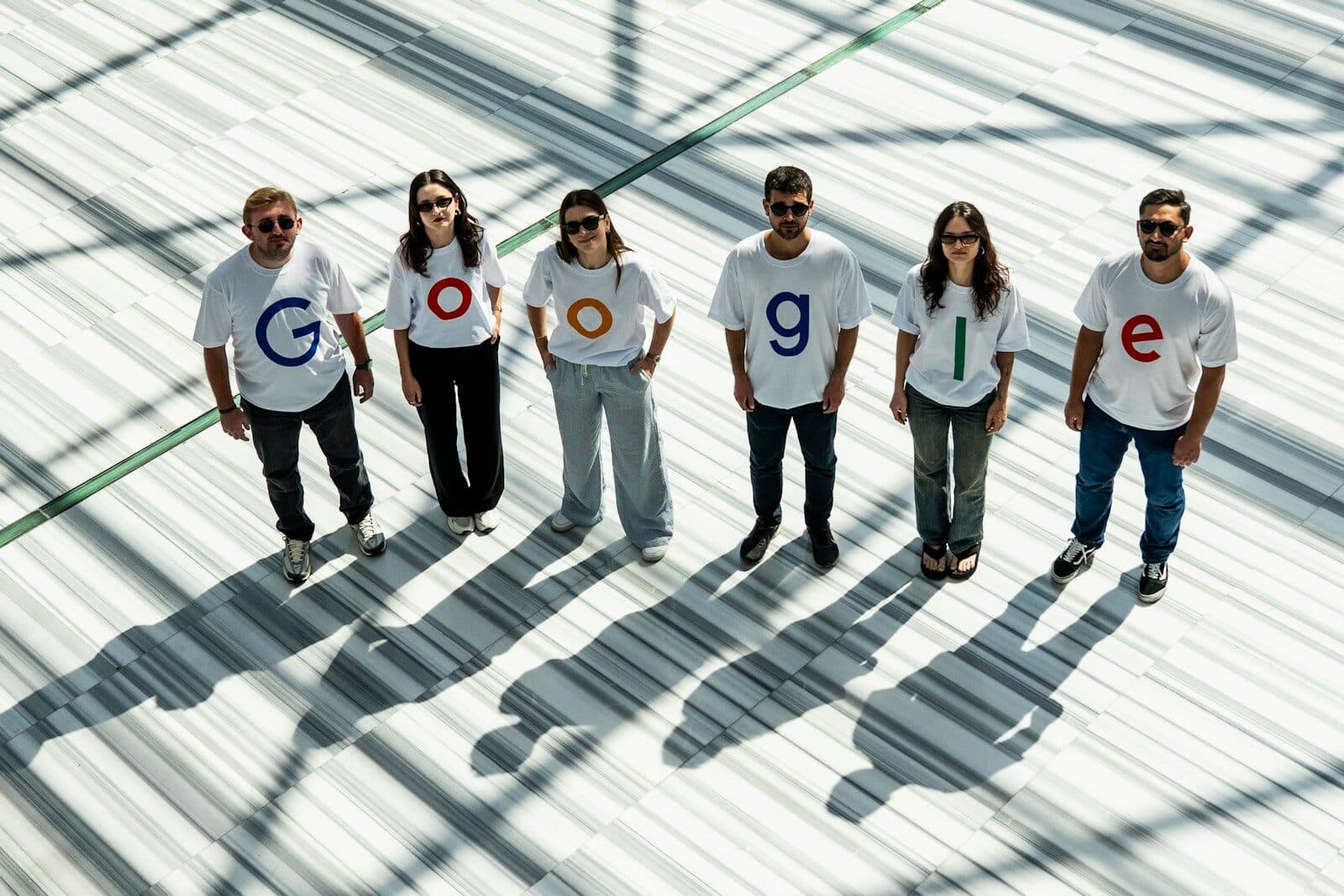 Six people wearing shirts spelling out google